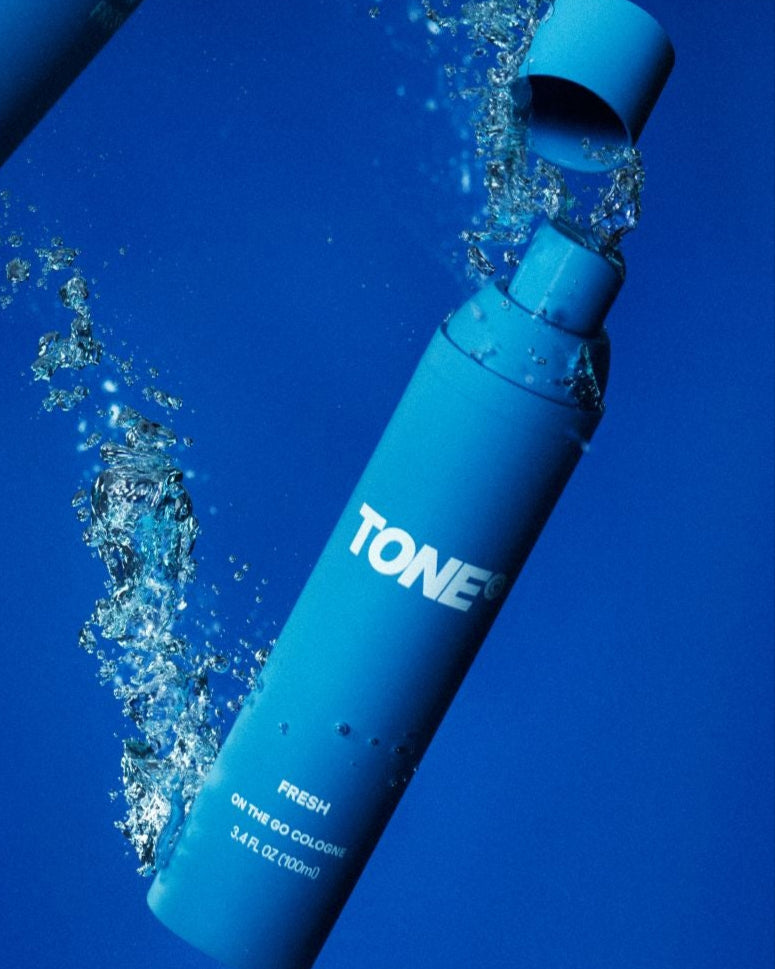 TONE Fresh On the go Cologne & Body Mist Bottle with water splashes on a blue background.