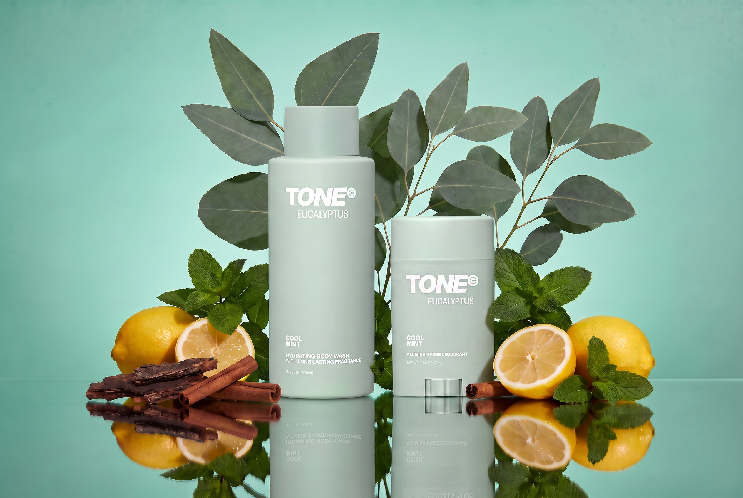 TONE EUCALYPTUS body care collection, styled with eucalyptus leaves, lemons, mint, and cinnamon sticks on a reflective surface against a mint green background.
